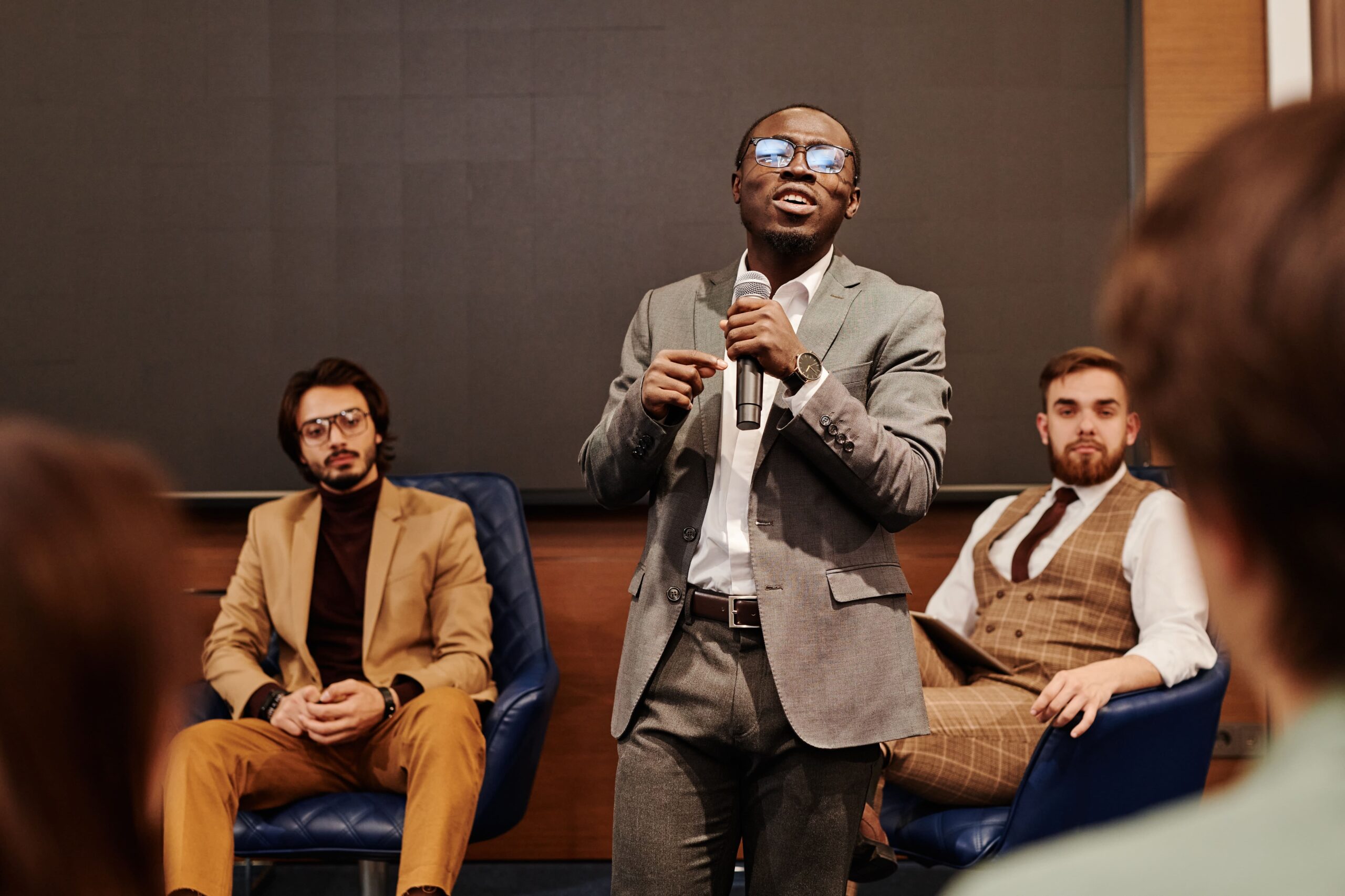 african man in suit talking holding a microphone