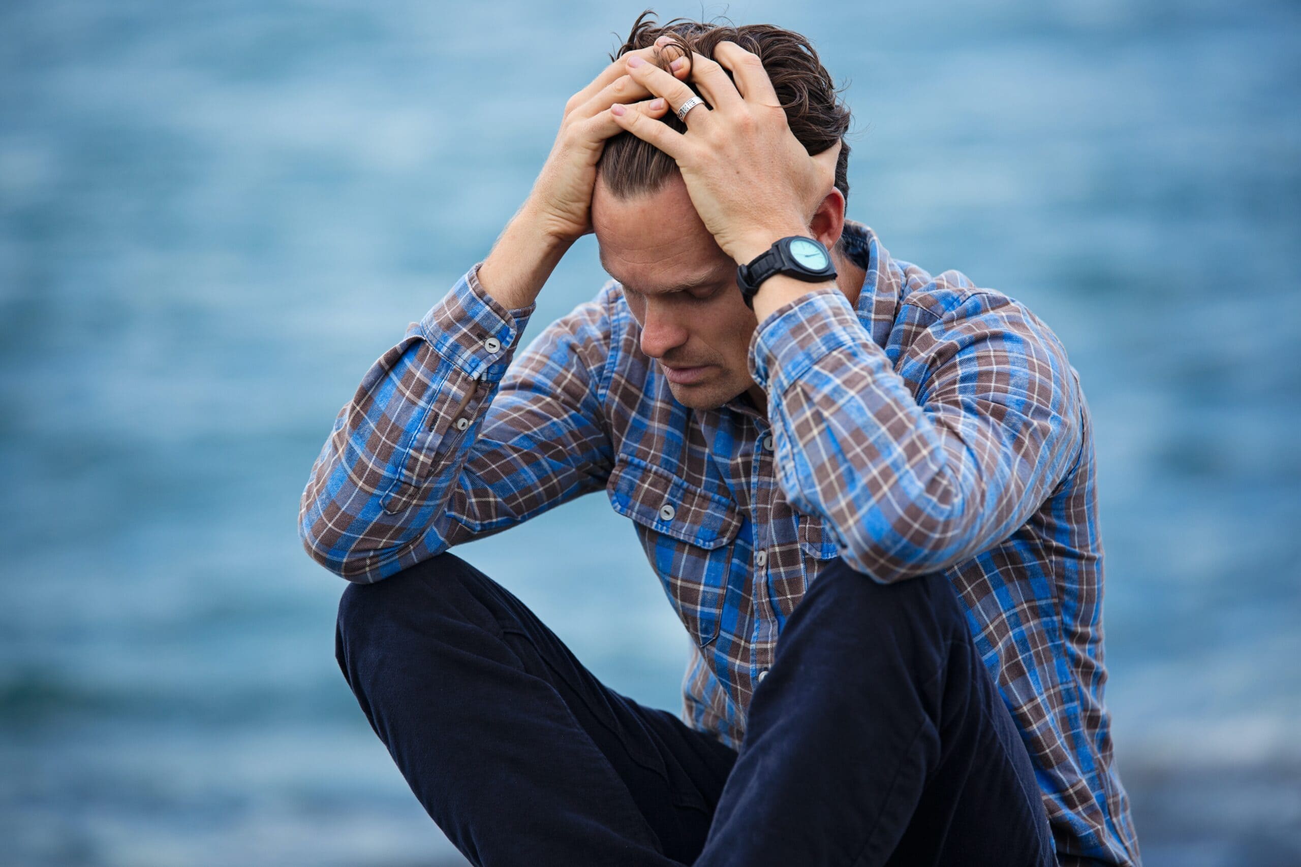 white man sitting with his hands in his hair, stressing. background