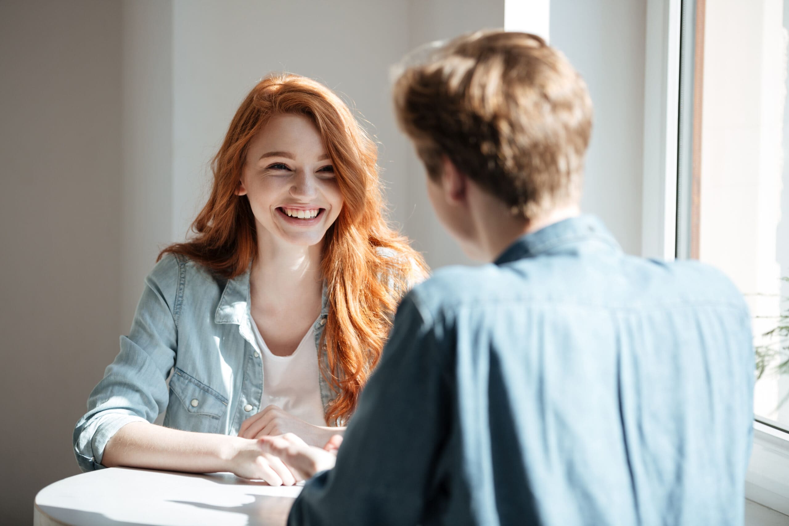 Young woman student laughing while talking in cafe