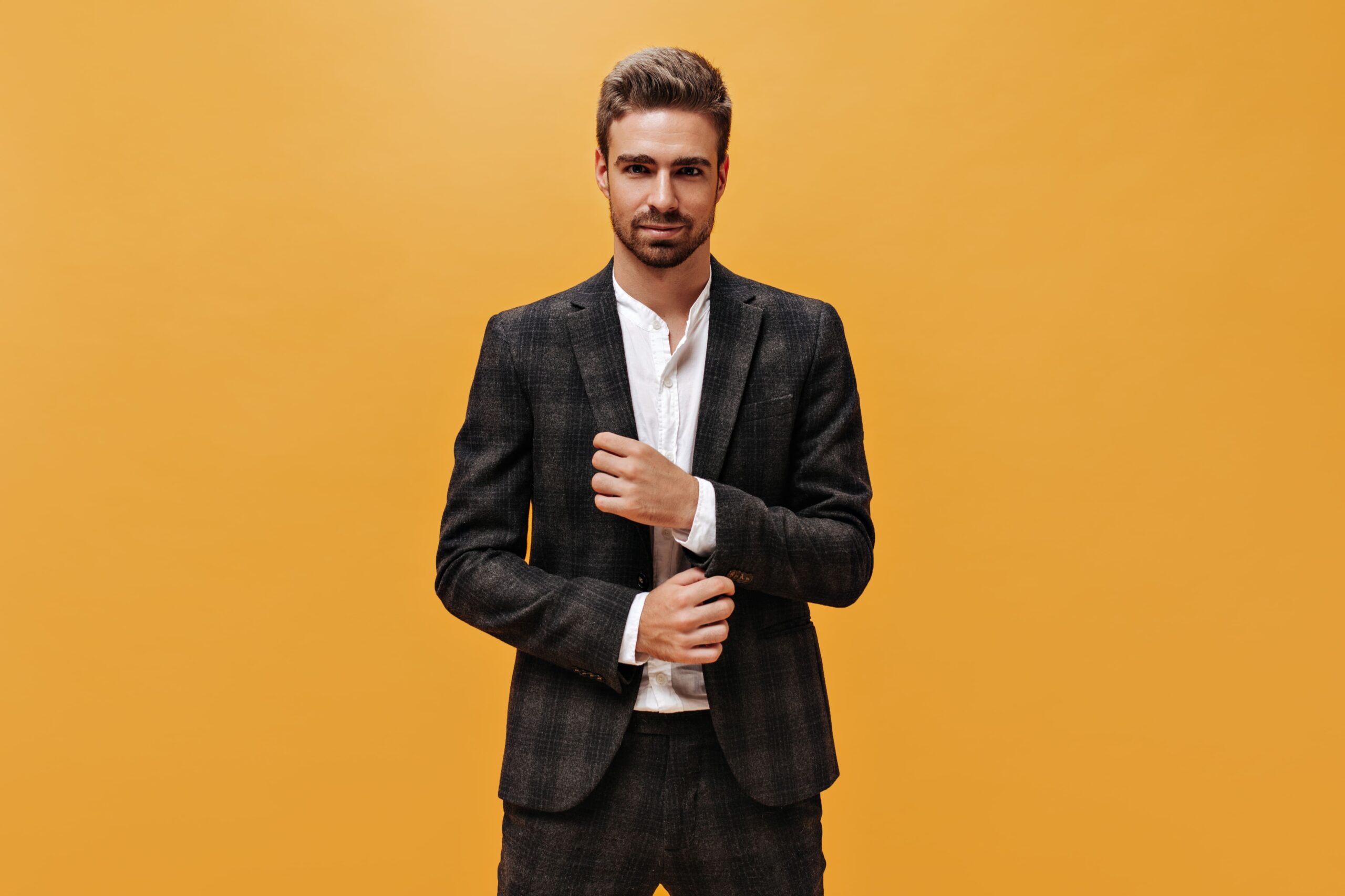 young-attractive-man-checkered-suit-looks-into-camera-orange-background-handsome-bearded-guy-poses-isolated