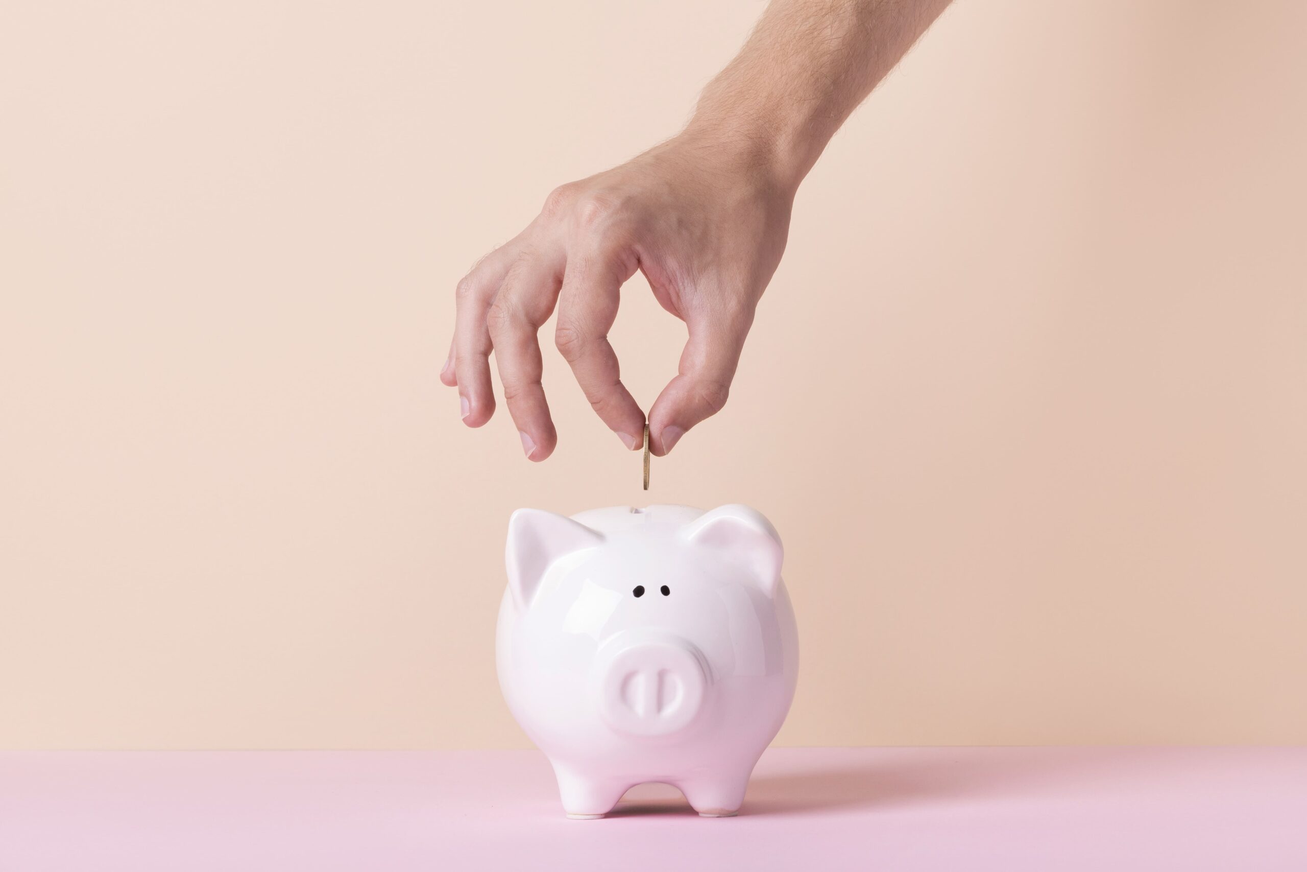 hand dropping coin into a piggy bank