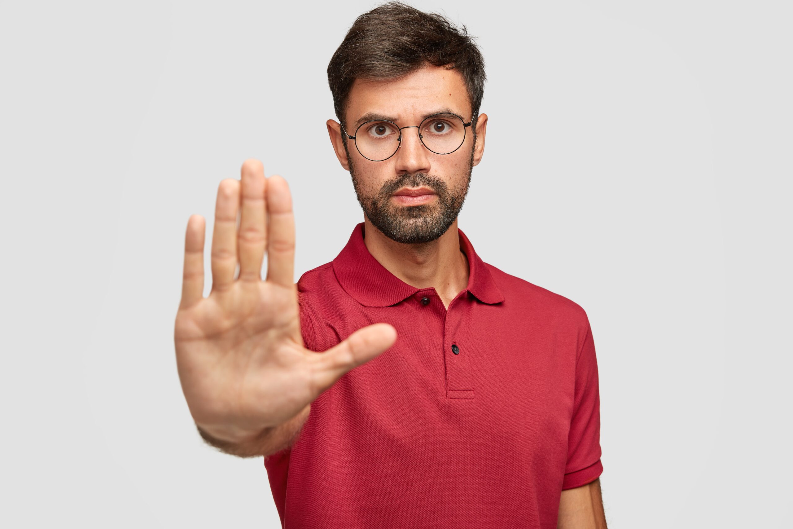 concerned-serious-bearded-man-round-eyewear-pulls-palm-towards-camera-stops-warns-you