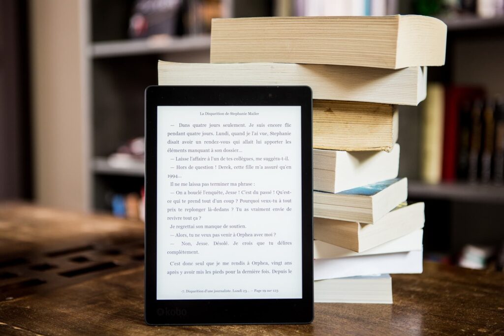 ipad-standing-in-front-of-pile of books-on wooden table